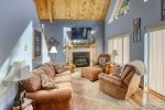 Knotty Pine Chalet living room with vaulted ceiling and wood burning fire place.